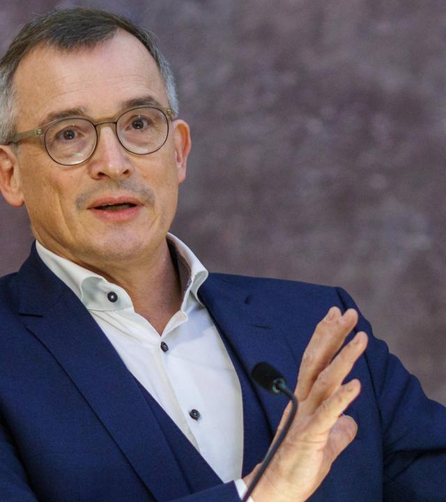 Mann gestikuliert beim Sprechen an einem Rednerpult