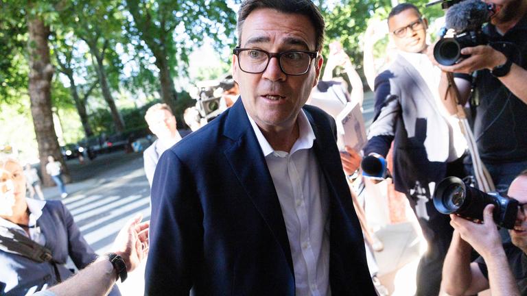Andy Burnham umringt von Pressepersonen.
