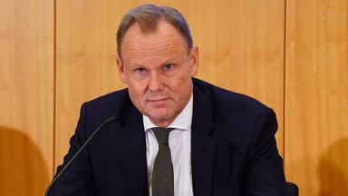 Andy Grote sitzt hinter einem Mikrofon bei einer Pressekonferenz.