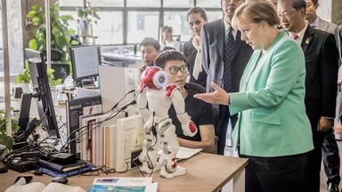 Shenzhen, China: Bundeskanzlerin Angela Merkel (CDU) besichtigt das Startup iCarbonX und spricht mit einem Programmierer am Computer. Archivbild