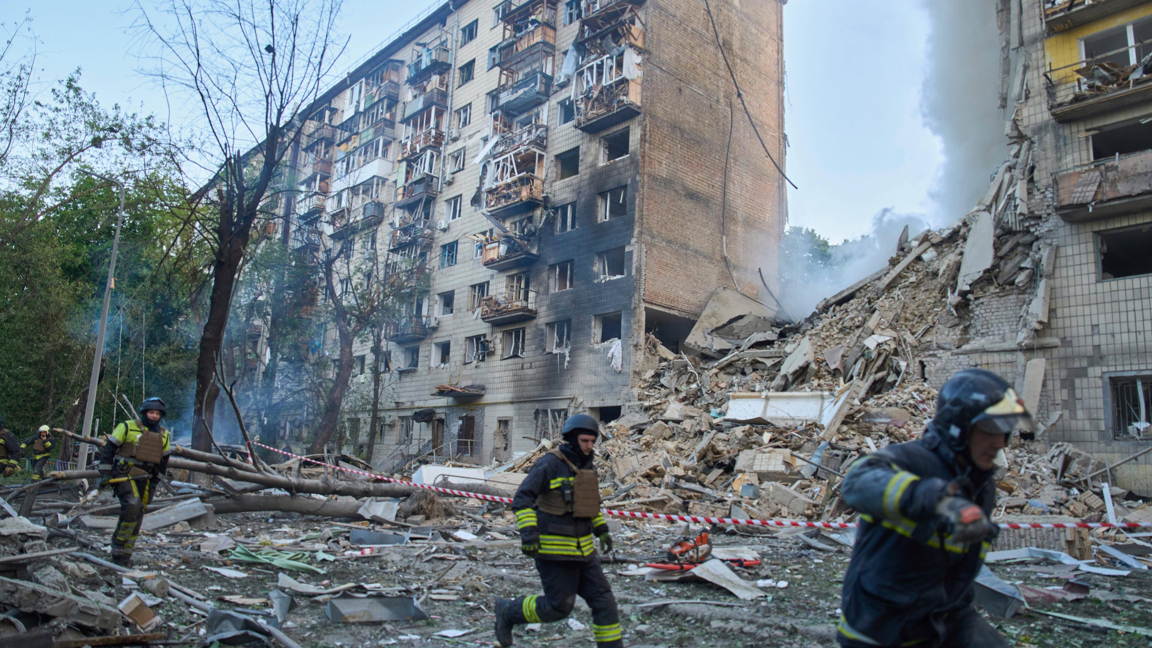 Rettungskräfte laufen vor einem zerstörten Gebäude in Kiew.