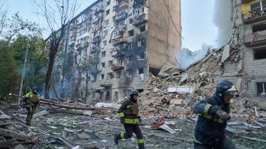 Rettungskräfte laufen vor einem zerstörten Gebäude in Kiew.