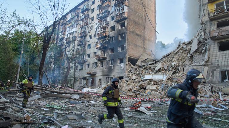Rettungskräfte laufen vor einem zerstörten Gebäude in Kiew.