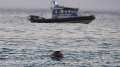  Ein Surfer paddelt zurück ans Ufer, während ein Polizeiboot nach einem Zwischenfall am Bondi Beach in Sydney auf dem Wasser patrouilliert.