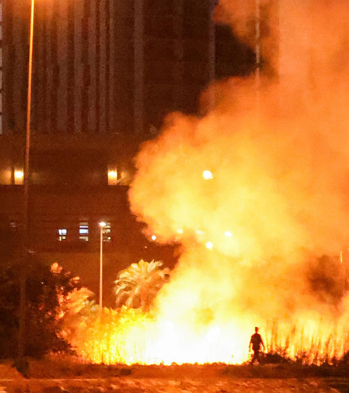 Am 17. März 2026 geht eine Person in der Nähe eines Feuers, das nach einem Drohnen- und Raketenangriff außerhalb des Geländes der US-Botschaft in der befestigten Grünen Zone von Bagdad brannte, wie Sicherheitsbeamte mitteilten. 