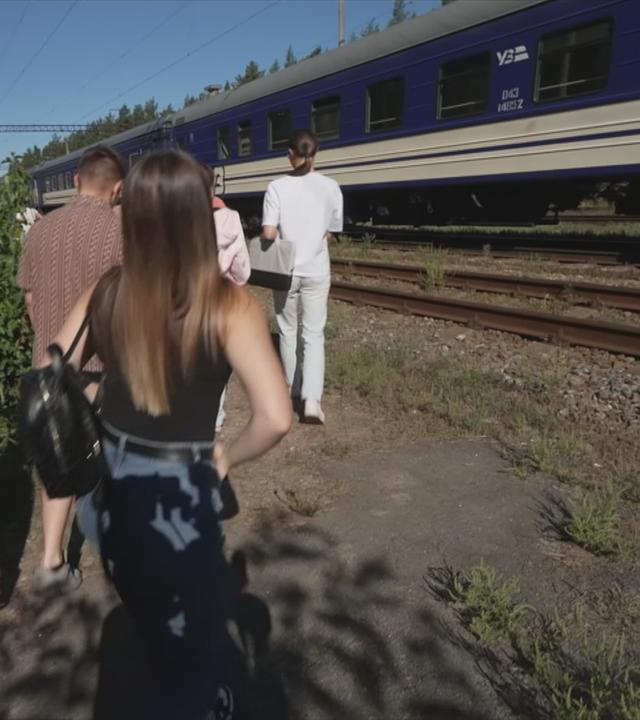 Ukraine: Menschen stehen vor einem Zug, der mitten auf der Strecke halten musste.