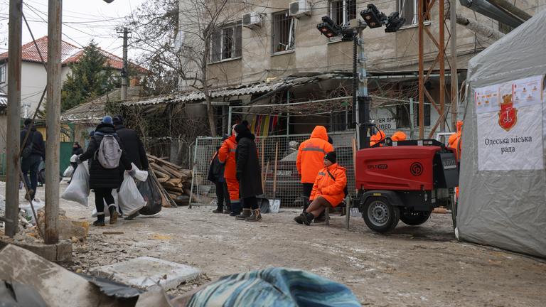 Ukrainische Einsatzkräfte und Arbeiter an einem beschädigten Wohnhaus nach einem russischen Drohnenangriff in Odesa.