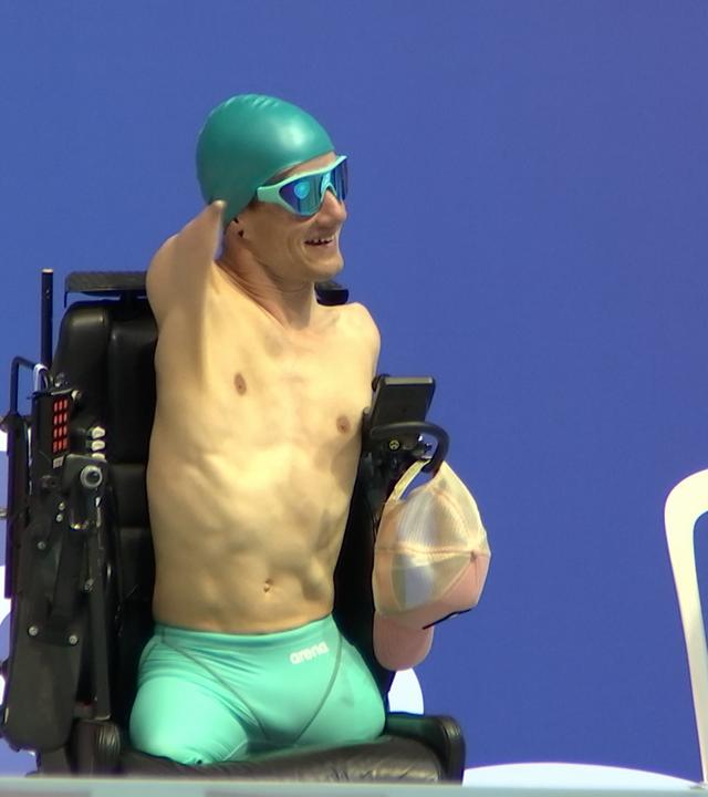 Janis McDavid wurde ohne Arme und Beine geboren. Er sitzt kurz vor dem Start in Badehose in einem Rollstuhl.