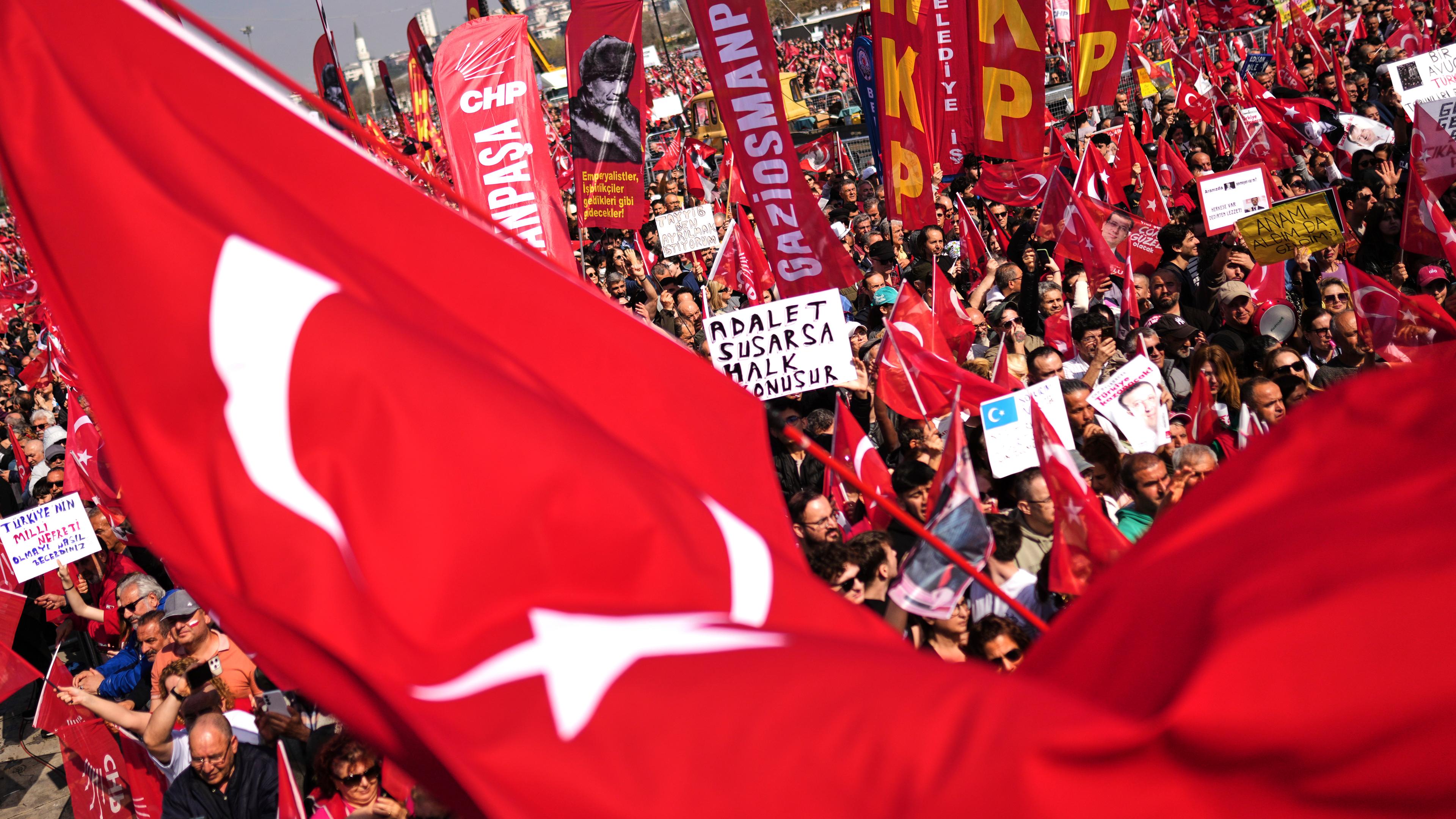 Demonstrierende Mneschen mit Plaketen und einigen Türkei-Flaggen