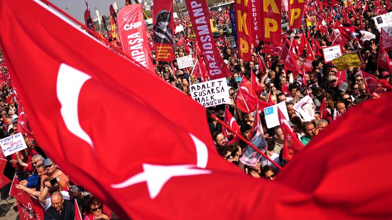 Demonstrierende Mneschen mit Plaketen und einigen Türkei-Flaggen