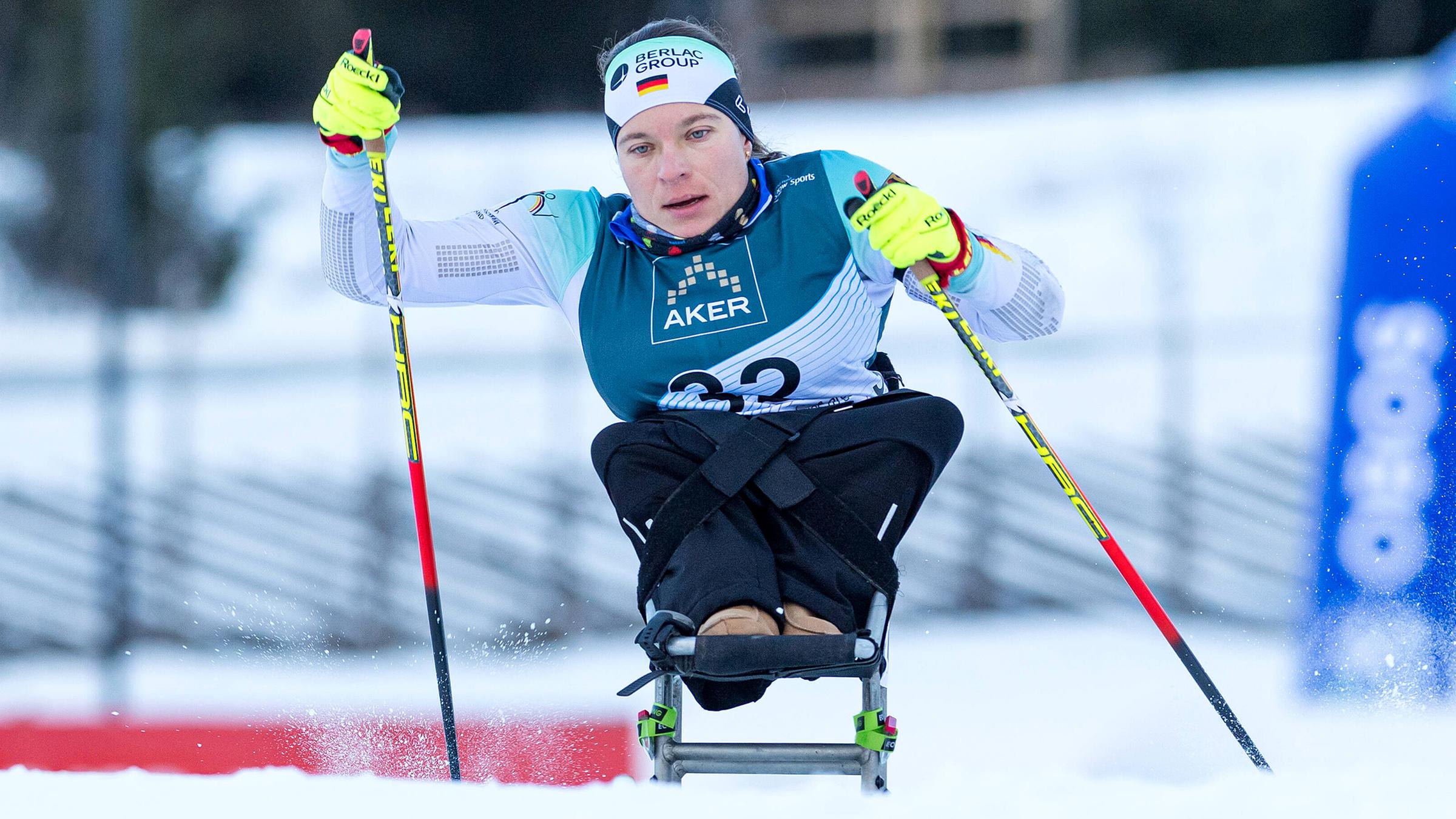Anja Wicker sitzend auf Langlaufskiern, in Aktion.