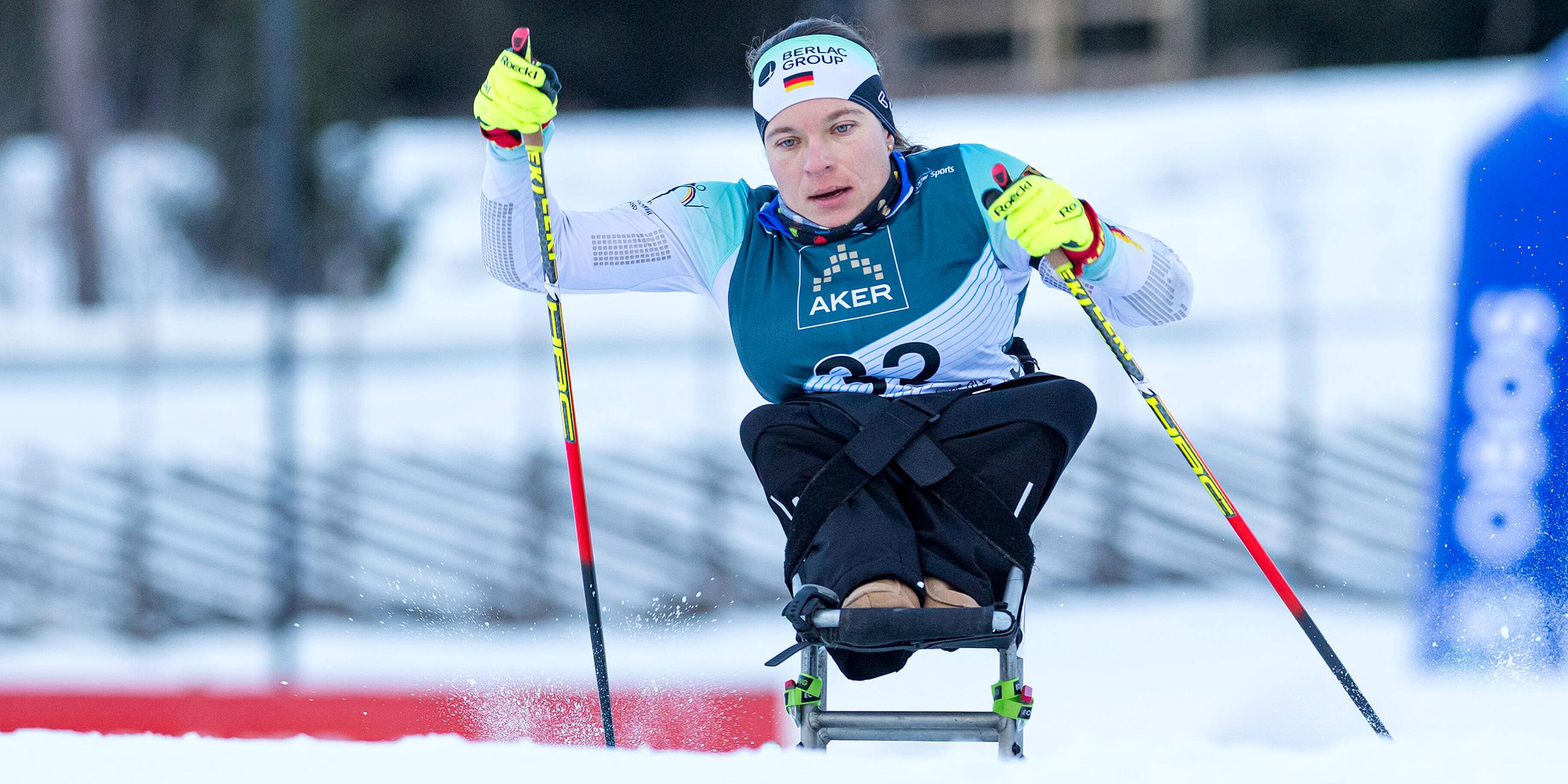 Anja Wicker sitzend auf Langlaufskiern, in Aktion.