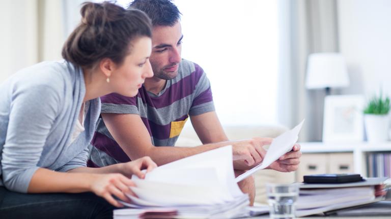 Zwei Personen sitzen an einem Tisch und besprechen ihre Finanzen.