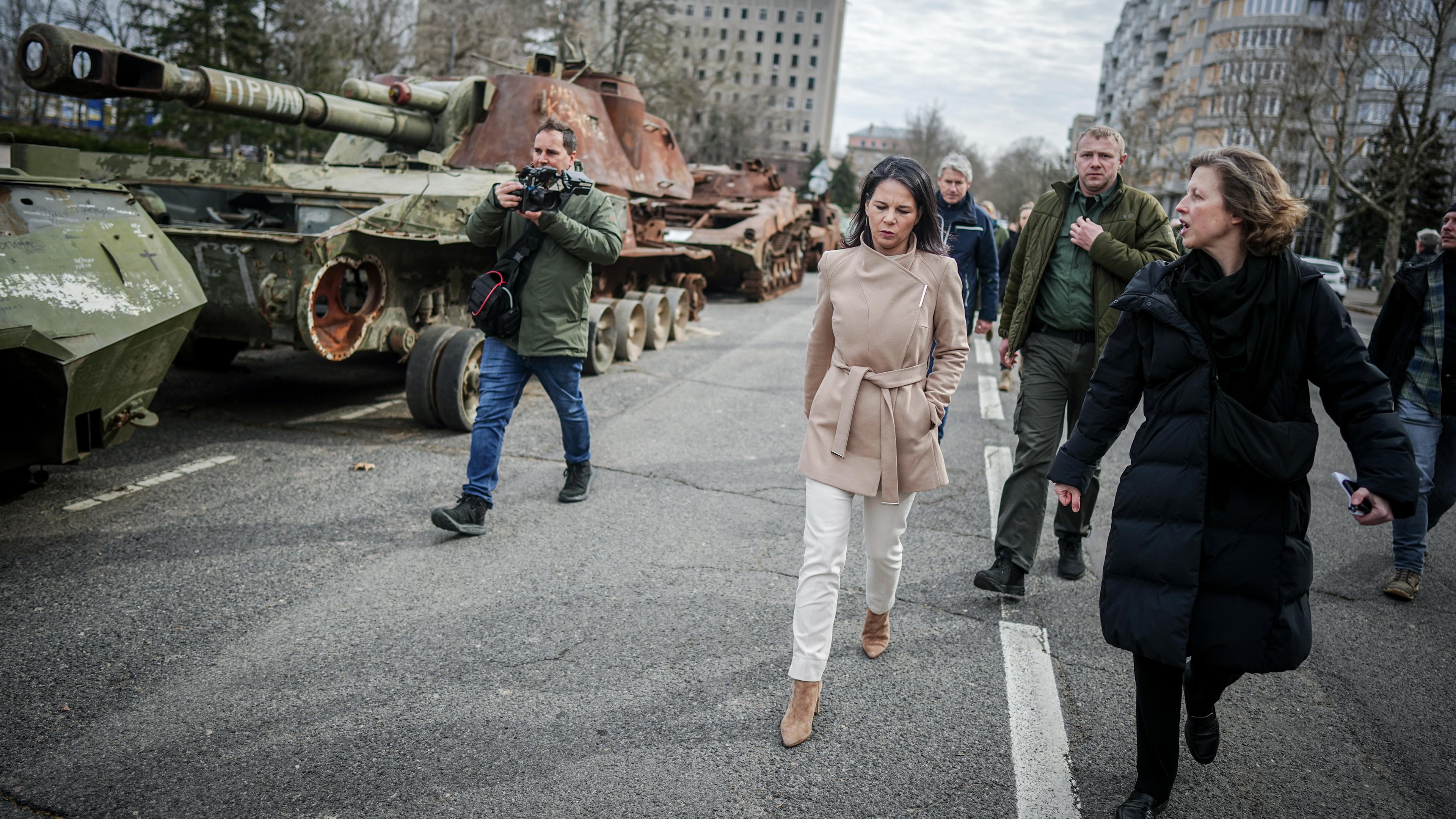 Annalena Baerbock geht bei ihrem Besuch des ehemaligen Sitz der Regionalverwaltung der Oblast Mykolajiw an zerstörten russischen Panzern vorbei am 25.02.2024.