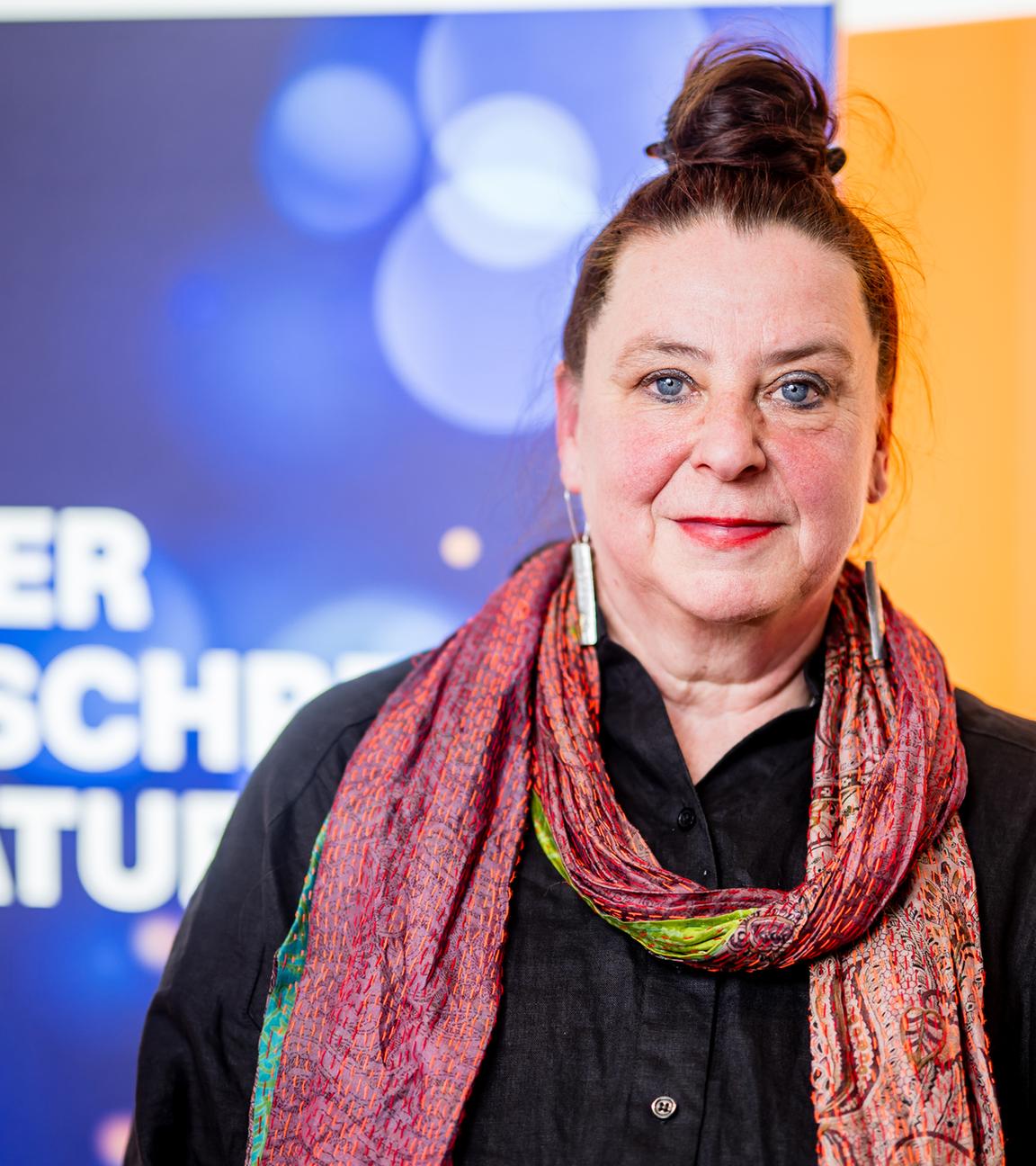 Frau lächelt auf einer Bühne in die Kamera.