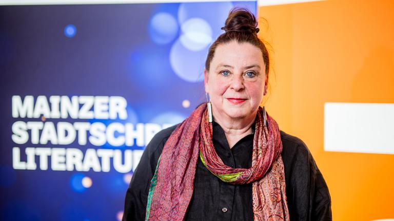 Frau lächelt auf einer Bühne in die Kamera.