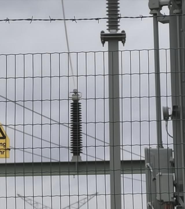 Zu sehen ist ein Umspannwerk, woein schlid hängt auf dem Hochspannung Lebensgefahr steht. 