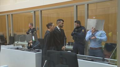 Angeklagter neben Anwälten und Polizisten.