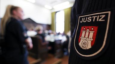 Mann mit Justizuniform. Abgebildet ist das Hamburger Wappen