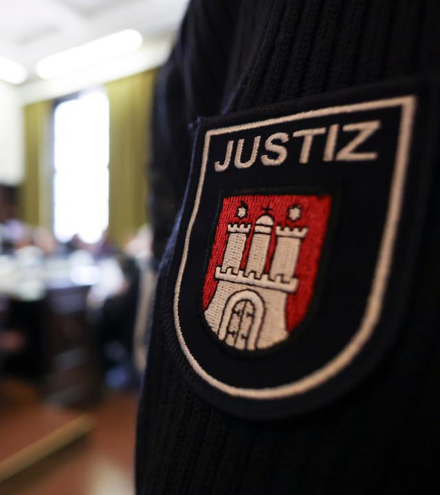 Mann mit Justizuniform. Abgebildet ist das Hamburger Wappen