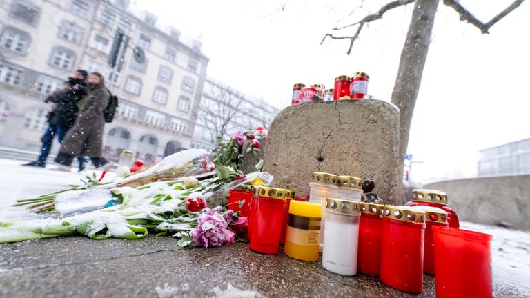 Bayern, München: Schnee fällt auf Kerzen und Blumen, die am Straßenrand in der Nähe des Stiglmaierplatzes in München abgelegt worden sind. Archivbild