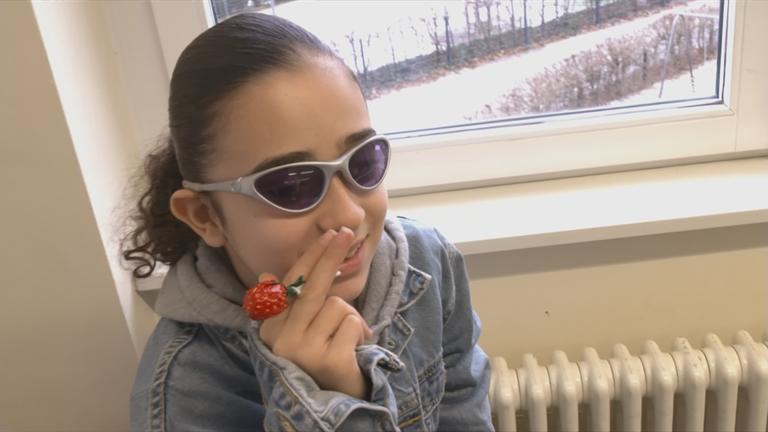 Auf dem Bild ist eine Schülerin zu sehen, die mit einem Lutscher eine Zigarette nachmacht.