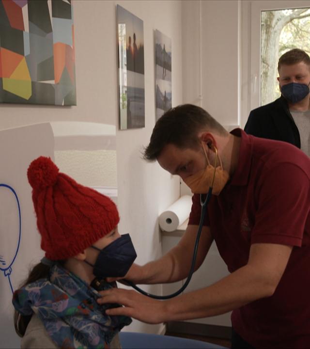 Kinderarzt hört kleines Mädchen mit Stetoskop ab