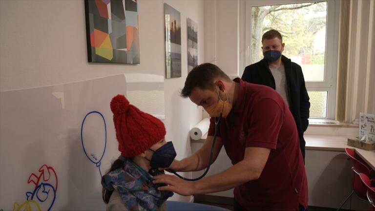 Kinderarzt hört kleines Mädchen mit Stetoskop ab