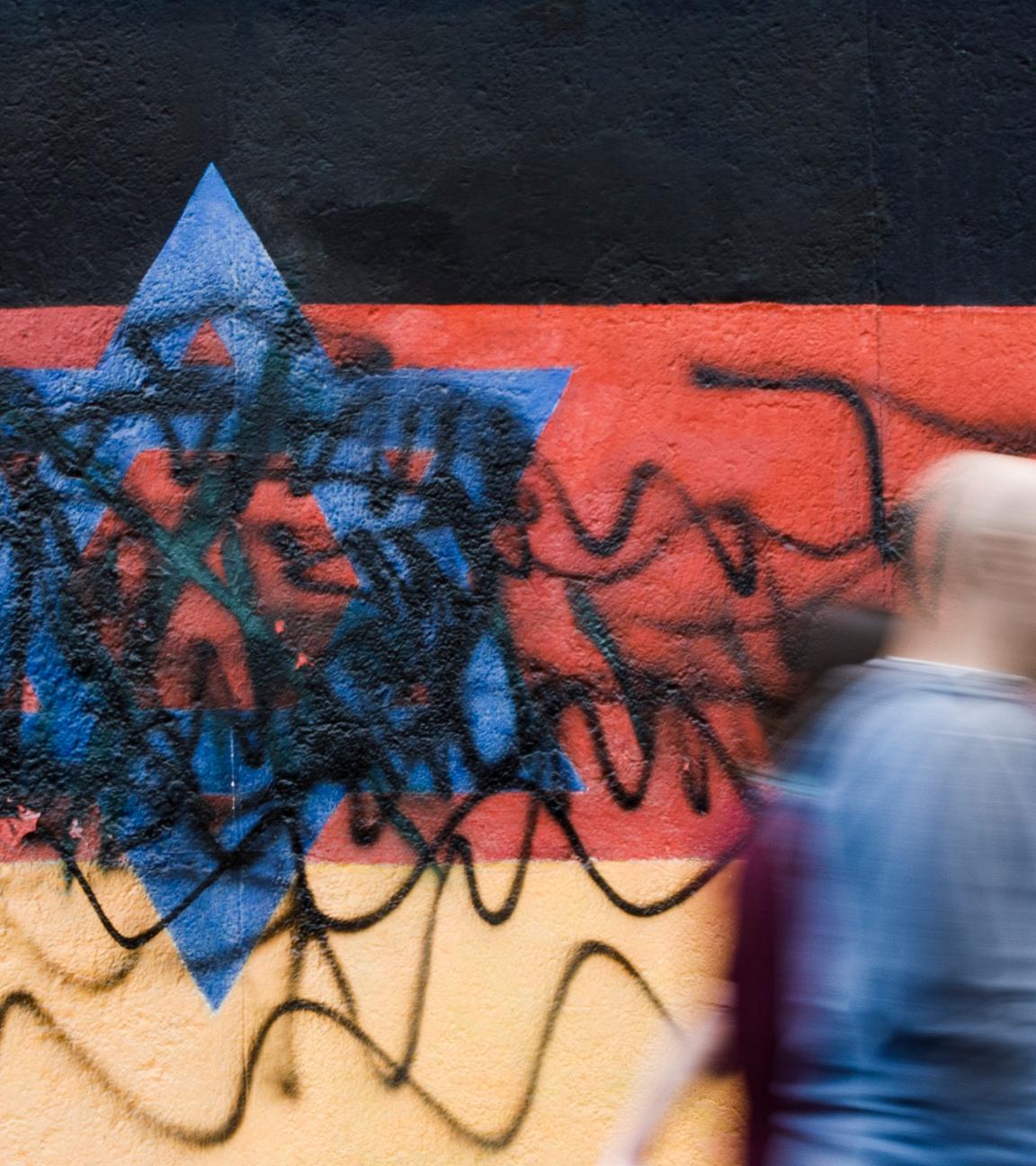 Archiv:  Passanten gehen an dem zerstörten Wandbild des Künstlers Günther Schäfer an der East Side Gallery vorbei. Das Wandbild «Vaterland», das die schwarz-rot-goldene Deutschlandfahne mit einem blauem Davidstern zeigt, wurde von Unbekannten mit schwarzen Graffitis beschmiert