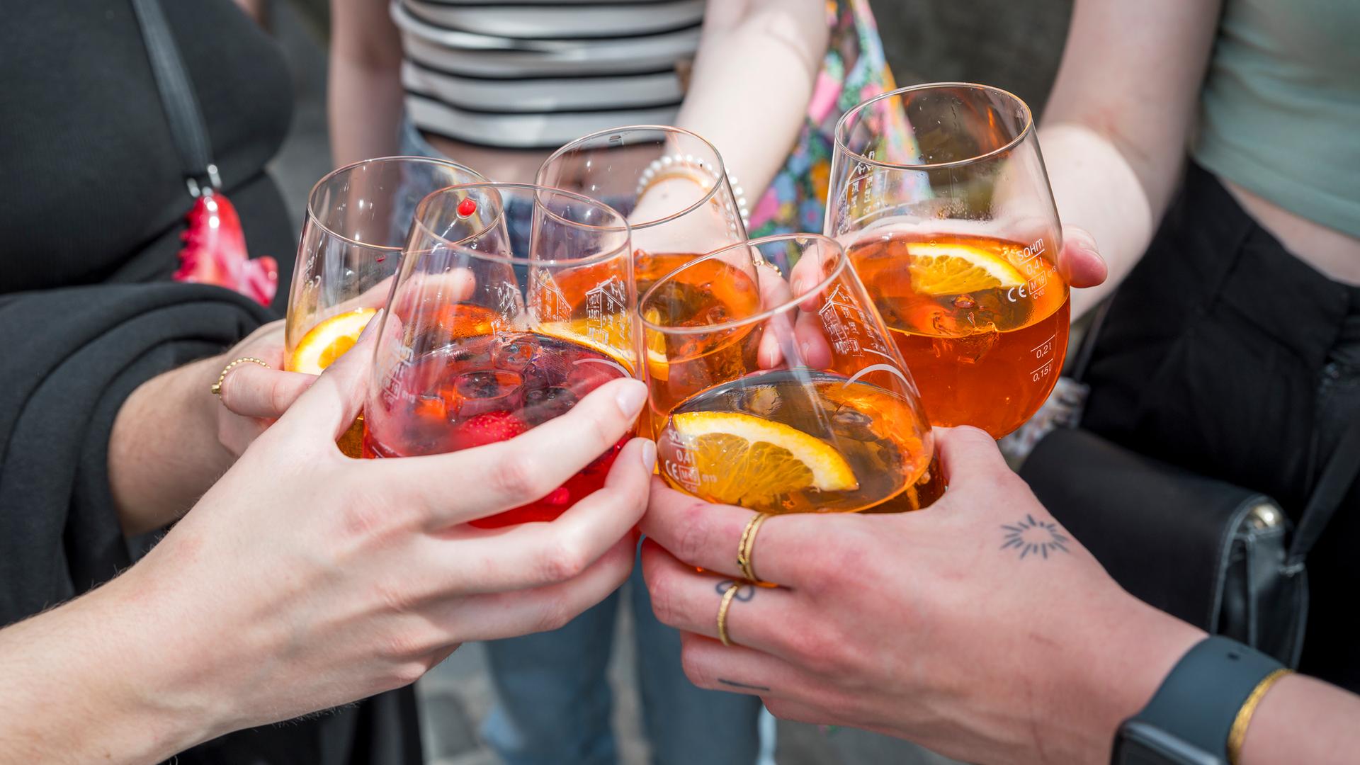  Fünf Personen stoßen mit ihren Gläsern mit Aperol Spritz an. 