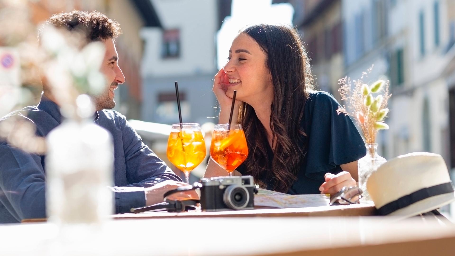 Paar sitzt mit Getränken in einem Straßencafé