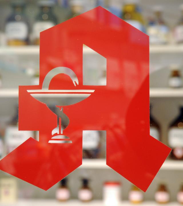 Das Logo an der Tür einer Apotheke.