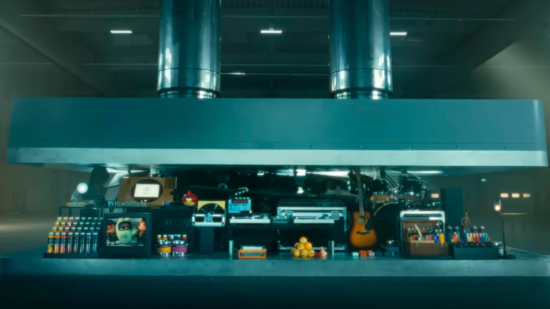 Eine riesige Presse zerdrückt Instrumente, eine Skulptur und Kameras.