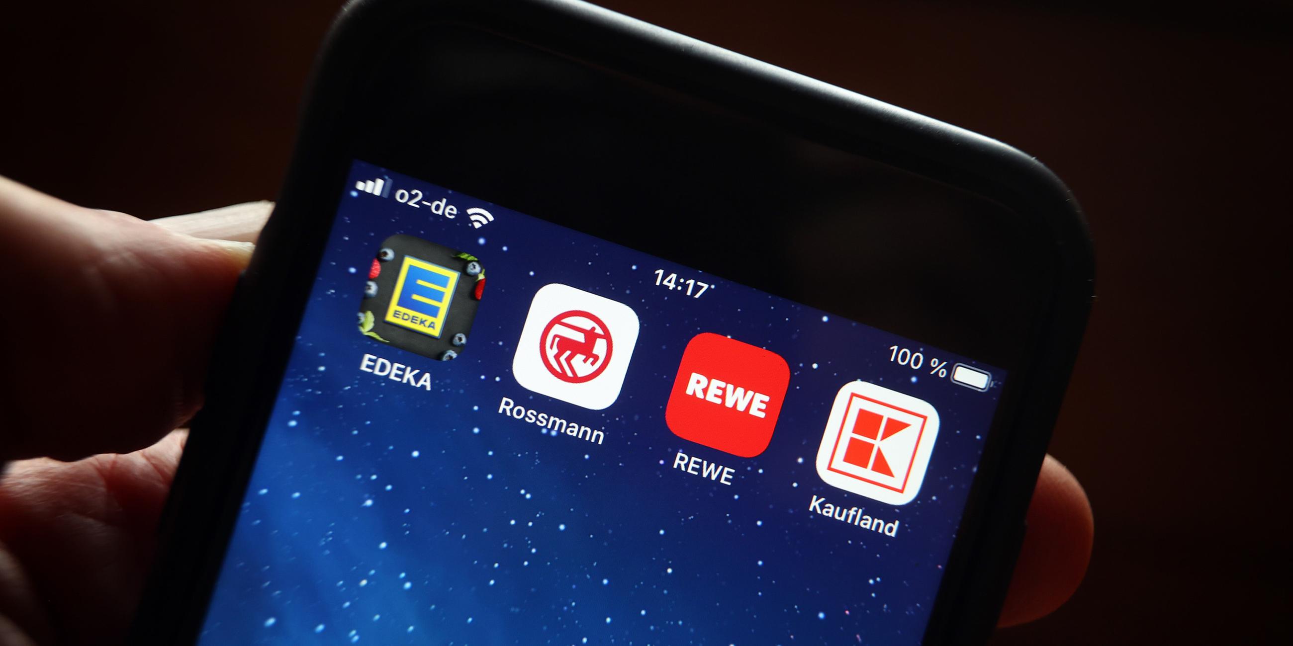Einkaufen mit Treue-App: Icons von den Handelsketten Edeka (l-r), Rossmann, REWE und Kaufland sind auf dem Display eines iPhones zu sehen.
