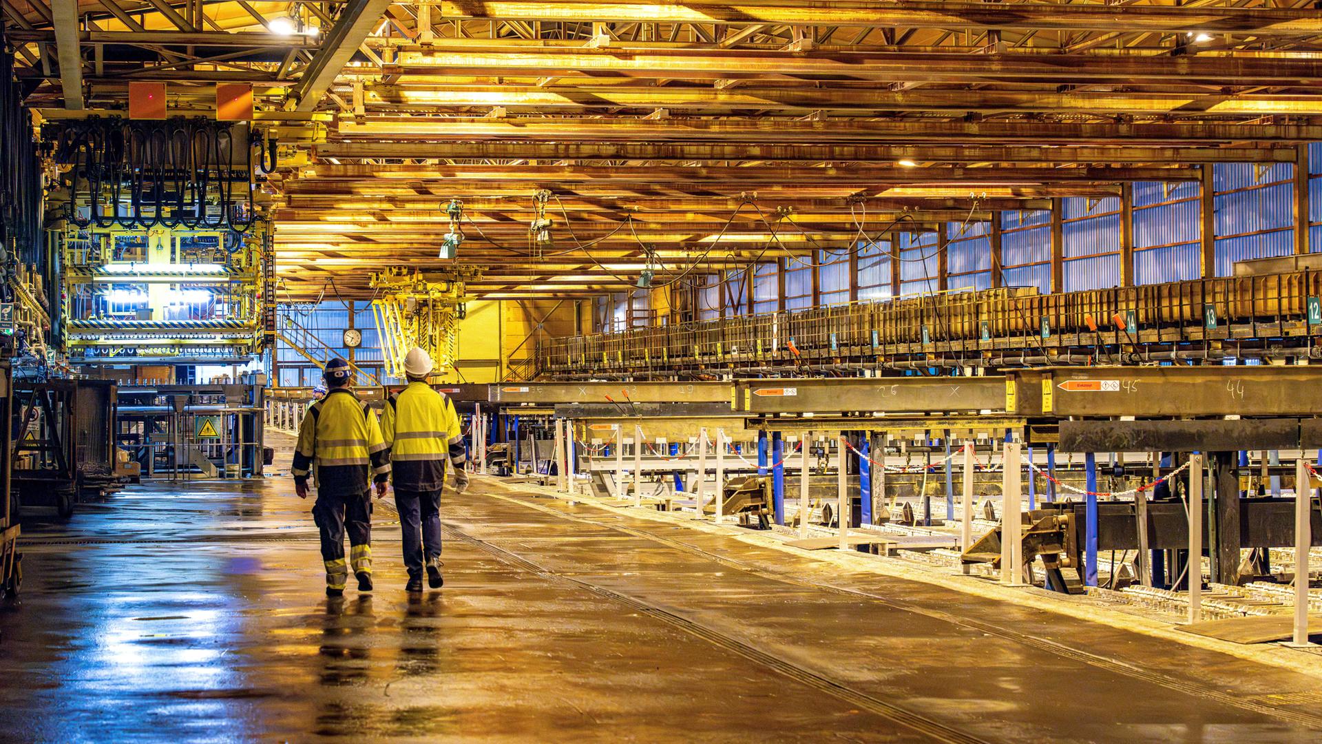 Arbeiter laufen durch eine Zinkhütte.