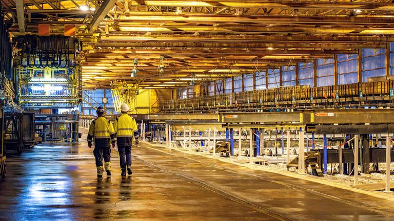 Arbeiter laufen durch eine Zinkhütte.