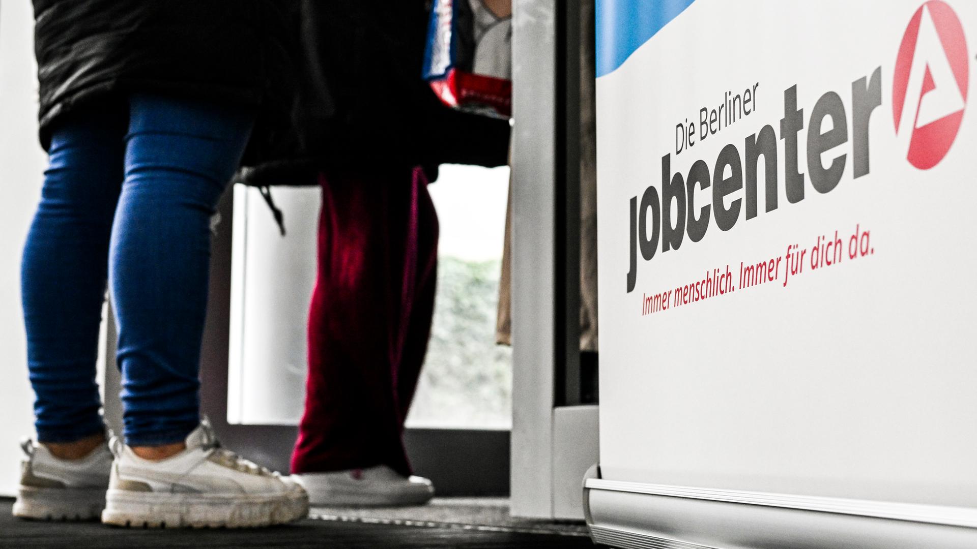 Symbolbild: Wartende Menschen stehen vor einem Jobcenter