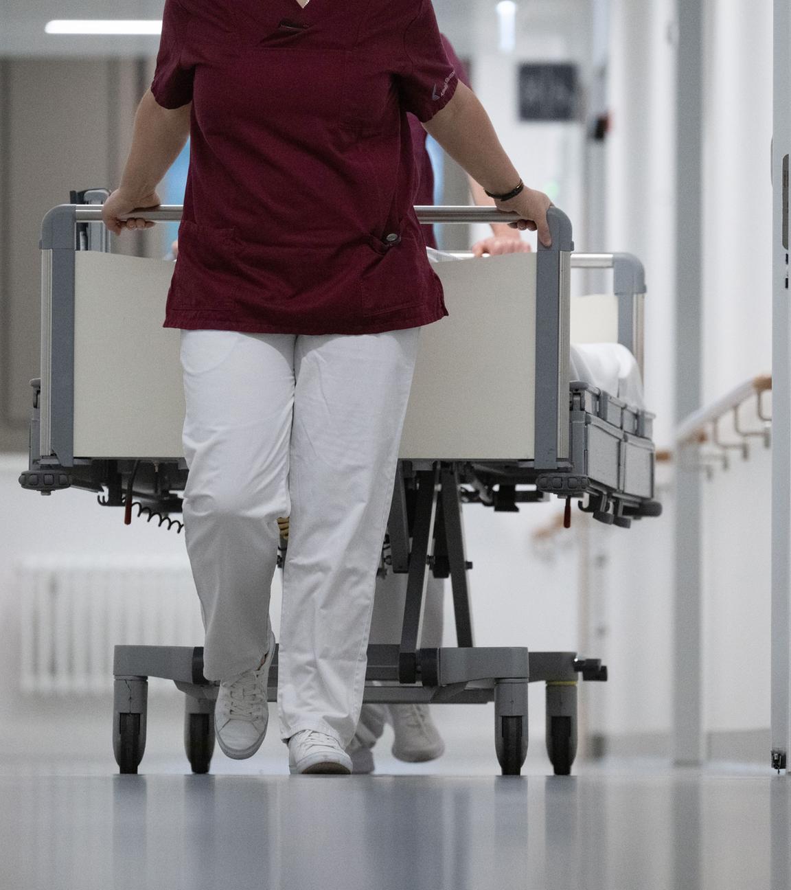 Krankenpfleger schieben ein Bett durch den Gang einer Klinikstation. (Symbolbild)