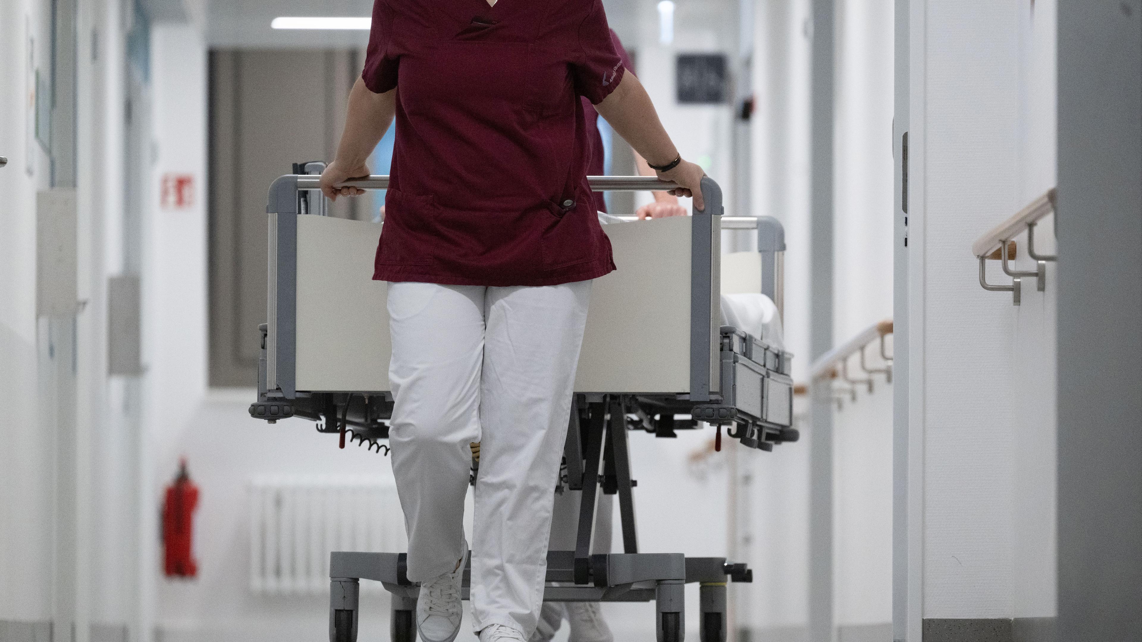 Krankenpfleger schieben ein Bett durch den Gang einer Klinikstation. (Symbolbild)