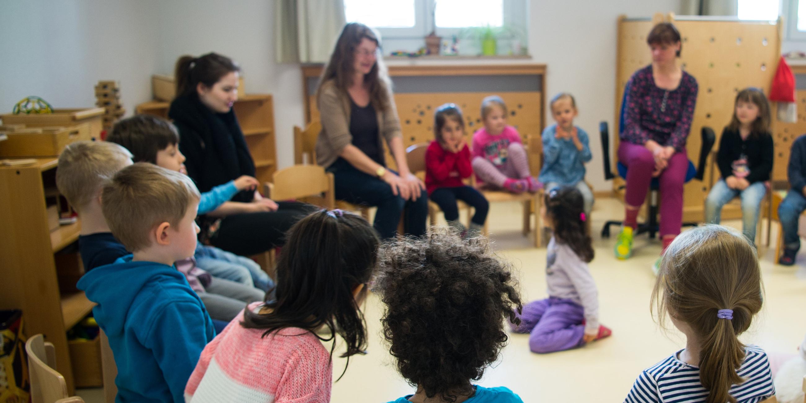 Kinder und Erzieherinnen im Stuhlkreis in einer Kita