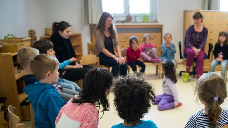 Kinder und Erzieherinnen im Stuhlkreis in einer Kita