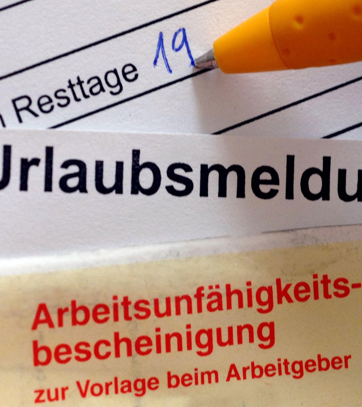 Übereinanderliegende Dokumente, wobei unten eine Urlaubsmeldung liegt, die von einer Arbeitsunfähigkeitsbescheinigung überdeckt wird