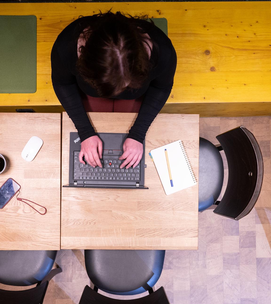 Eine Frau sitzt im Homeoffice am Küchentisch und arbeitet an einem Laptop (gestellte Szene).