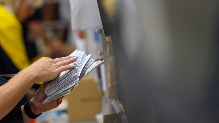 Mitarbeiter der Deutschen Post sortieren im Zustellstützpunkt Magdeburg-Buckau Briefe.
