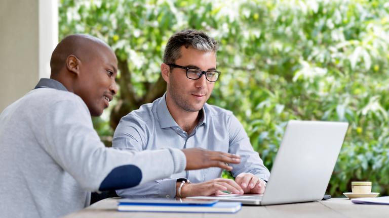 Zwei Männer sitzen am Laptop (Symbolfoto)