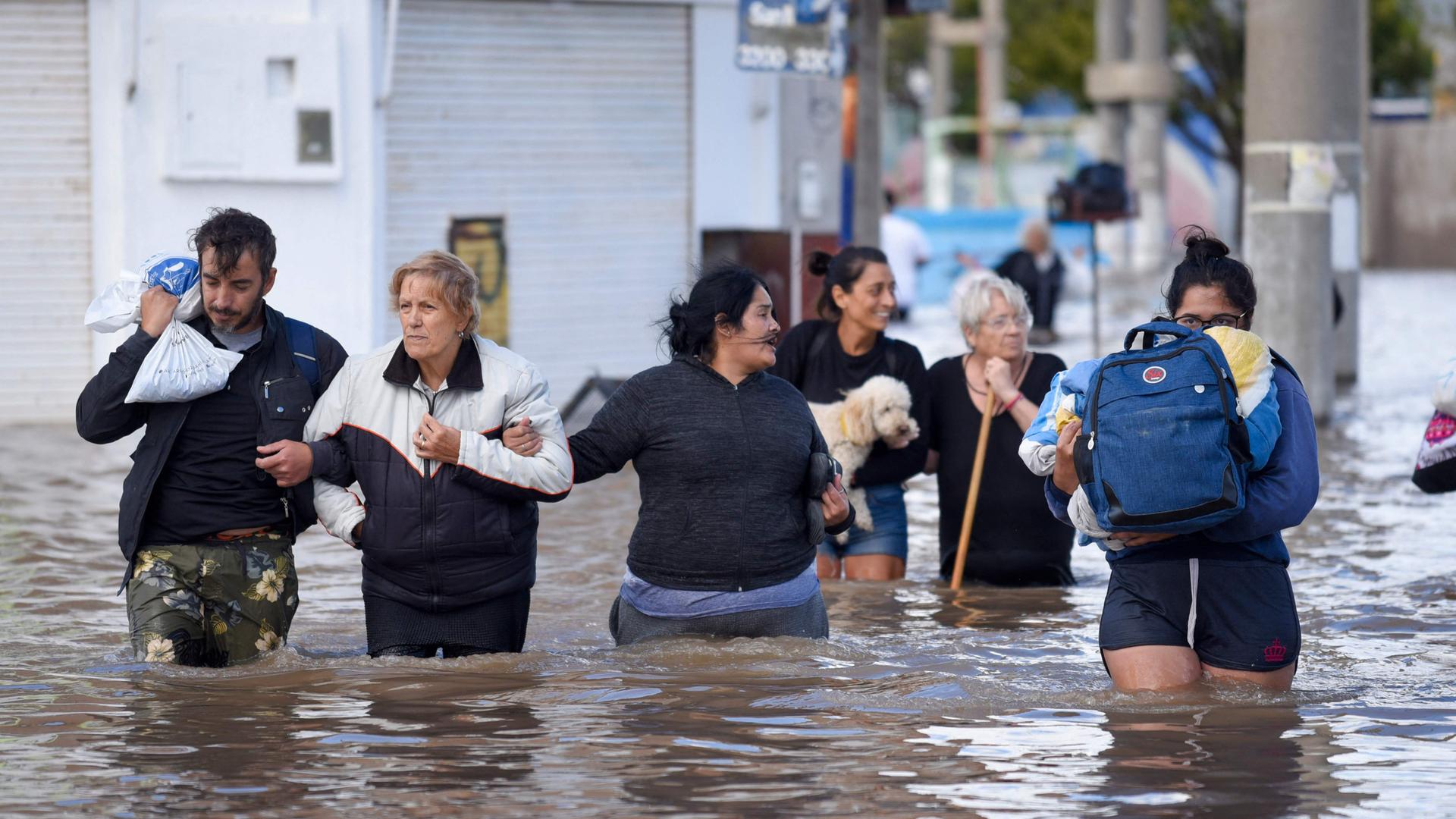 Menschen waten in Bahia Blanca durch überflutetes Gebiet.