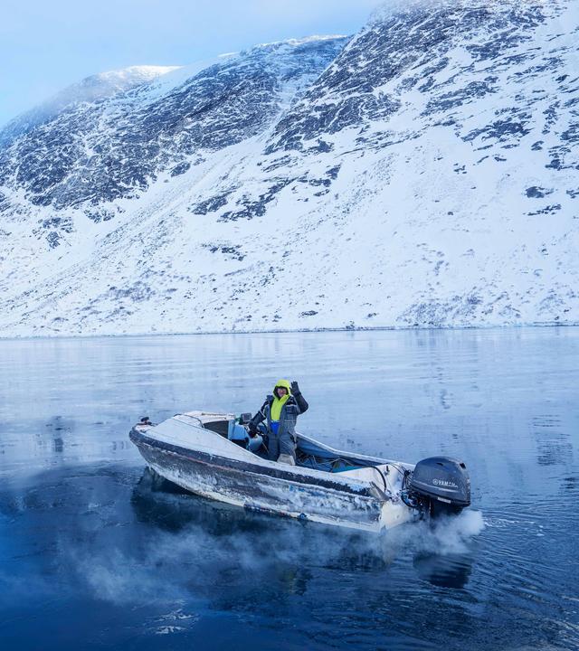 Ein Fischer fährt auf einem Boot durch eine zugefrorene Meeresbucht außerhalb von Nuuk. Grönland liegt zwischen dem Nordatlantik und dem Polarmeer und ist die größte Insel der Welt.