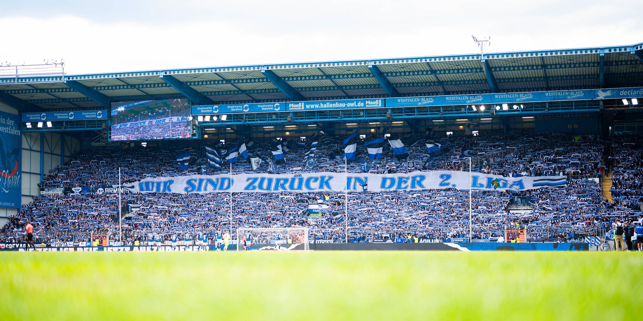 Fans von Arminia Bielefeld halten ein Banner mit der Aufschrift "Wir sind zurück in der 2. Liga. 