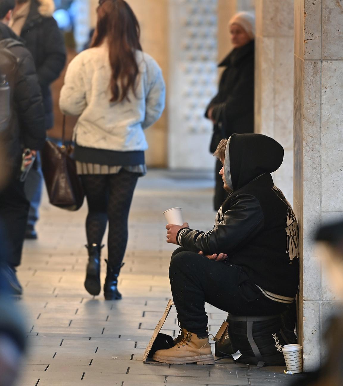 Ein junger Mann sitzt auf der Straße und bettelt.