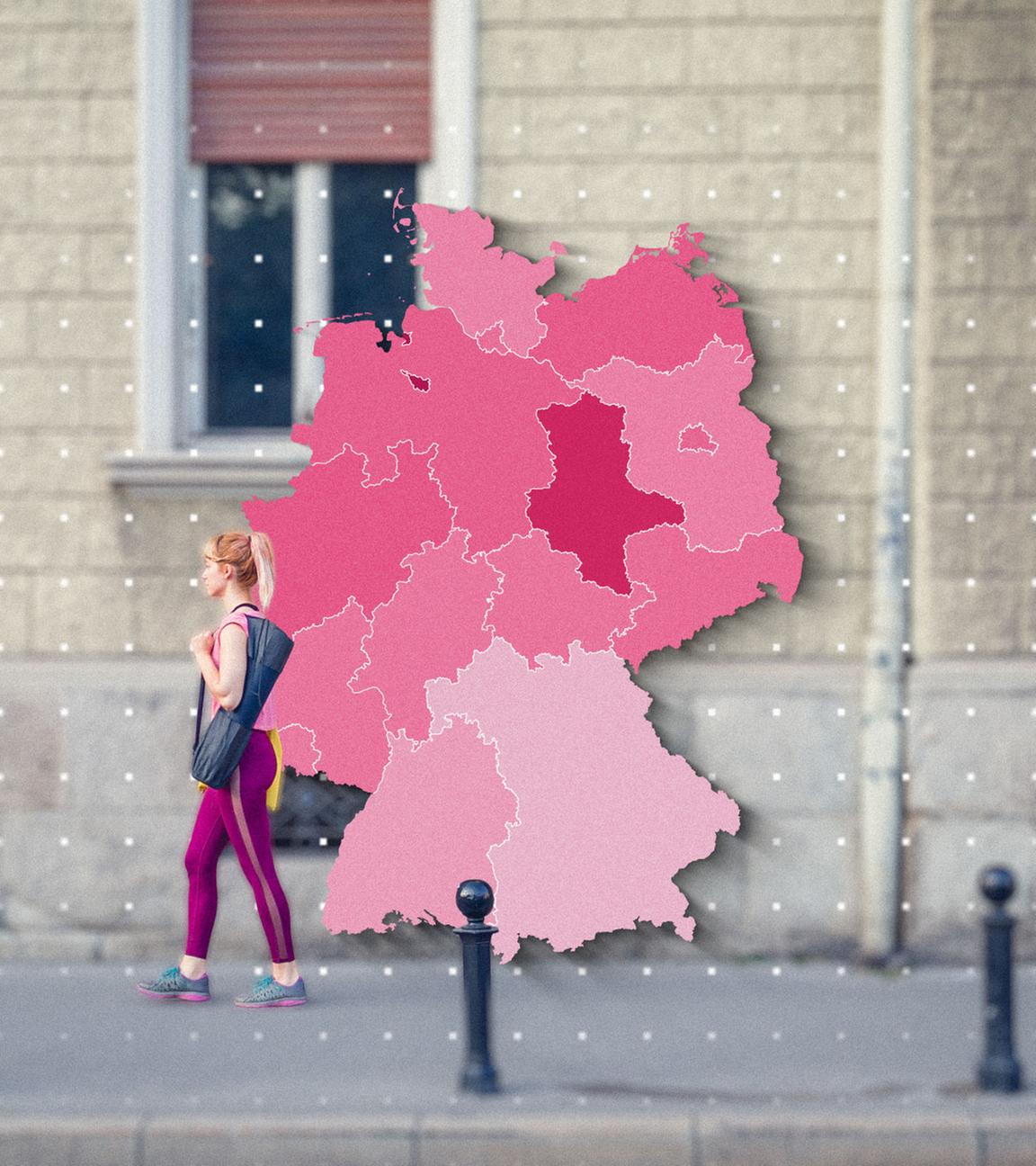 Eine Frau läuft vor der Fassade eines Gebäudes entlang. Drauf ist die Grafik einer Deutschlandkarte zu sehen.